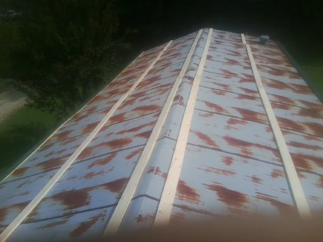 Rusted metal roof panels with new wood purlins before replacement — Storm Damage Roof Repair in Crab Orchard by Roofing Brothers